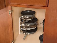 pots and pans are stacked in the corner of a kitchen cabinet with wooden drawers