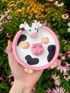 a hand holding a pink and white toy with a cow on it