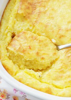 a close up of a casserole in a white dish with a spoon inside