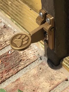 a door handle with a dog paw print on it and a brick walkway behind it