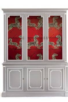 a white cabinet with zebras painted on the doors and side panels, in front of a red background