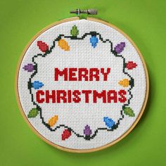 a cross stitch christmas ornament hanging on a green wall with the words merry christmas