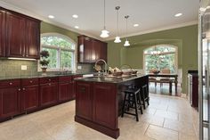 a large kitchen with dark wood cabinets and marble counter tops, along with bar stools