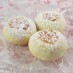 three powdered pastries sitting on top of a glass plate