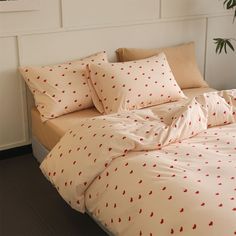 a bed with red hearts on it in a room next to a potted plant