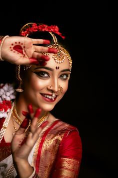 a woman in red and gold is holding her hand up to her face with the other hand