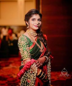 a woman in a green and red sari with jewelry on her neck, posing for the camera