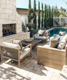 an outdoor living area with couches, chairs and a fire place next to a swimming pool