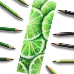 several pencils are lined up in front of a bookmark with lime slices on it