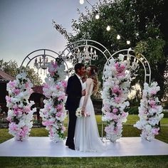 a bride and groom are standing in front of a floral arch for their wedding ceremony