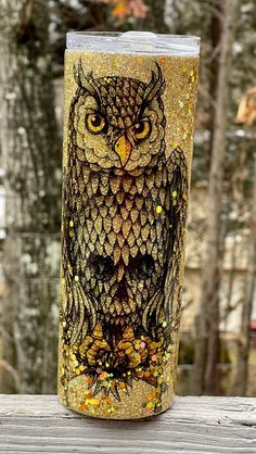 an owl is painted on the side of a cup with gold flakes and glitters