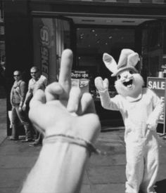 a person in bunny suit giving the peace sign with their hand and other people standing around