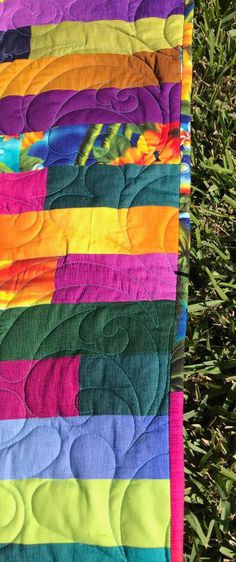 a multicolored quilt is laying on the grass