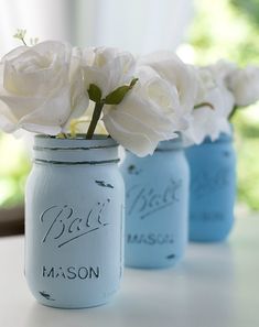 three blue mason jars with white roses in them