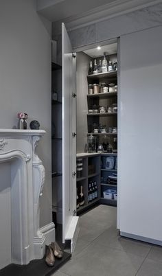 a white fireplace in a living room next to a wall with shelves on each side