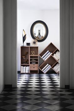 an open door leading into a room with black and white checkered flooring, bookshelf and mirror on the wall