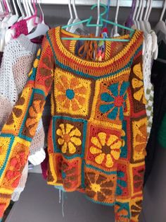 colorful crocheted sweaters hanging on clothes rack