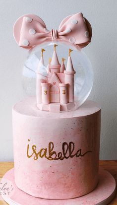 there is a pink cake with a castle in the middle and a bow on top