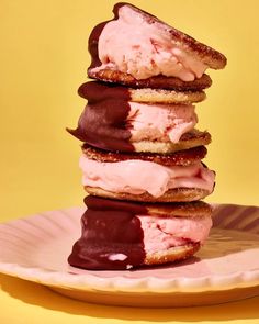 a stack of ice cream sandwiches sitting on top of a pink plate next to a yellow wall