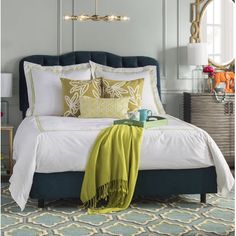 a bed with white sheets and green throw pillows on top of it in a bedroom