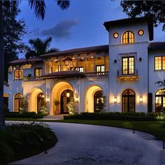 a large white house with lots of windows and lights on it's front entrance