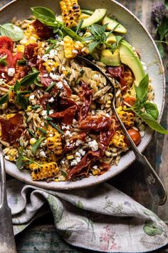 a bowl filled with pasta and vegetables on top of a table next to utensils