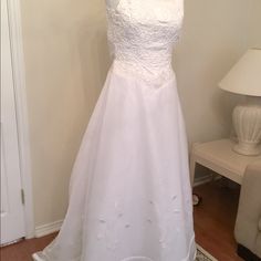 a wedding dress hanging on a hanger next to a lamp in a living room