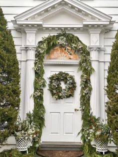 a white door decorated with wreaths and greenery