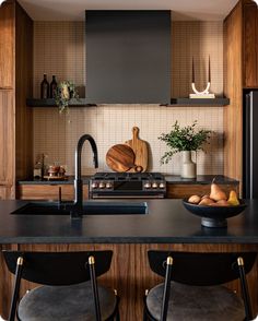 a kitchen with wooden cabinets and black counter tops, two stools are in front of the sink