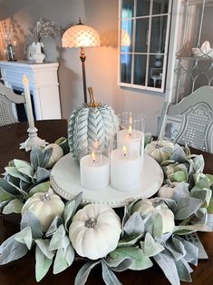 a table with candles and some white pumpkins on it