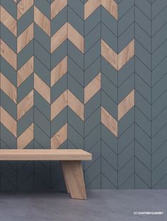 a wooden bench sitting in front of a wall with wood chevrons on it