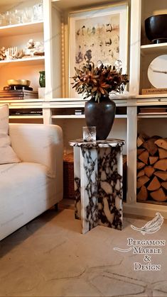 a white couch sitting next to a table with a black vase on top of it