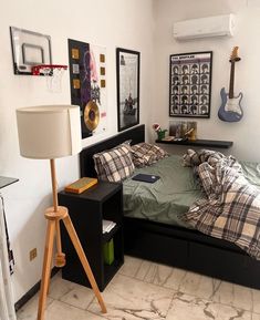 a bed room with a neatly made bed next to a lamp and pictures on the wall