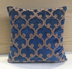 a blue and gold pillow sitting on top of a wooden floor