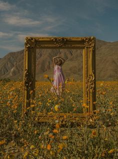 a woman standing in a field with a frame on it's face and her hands behind her head