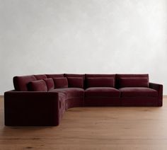 a large red couch sitting on top of a wooden floor next to a white wall