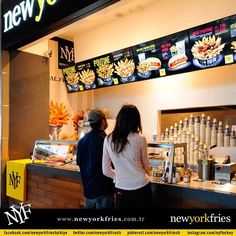 two people are standing in front of a new york's hot dog restaurant counter