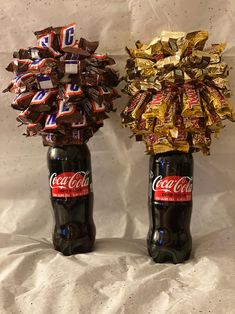 two coca - cola bottles decorated with ribbons and chocolates are sitting side by side