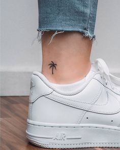 a small palm tree tattoo on the side of a woman's foot, behind her left ankle