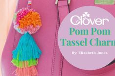 a pink purse with pom pom tassel charms hanging from it's handles