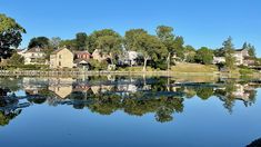 a body of water with houses in the background and trees on both sides, surrounded by land