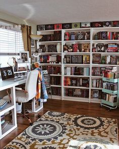 a home office with bookshelves full of books and a rug on the floor