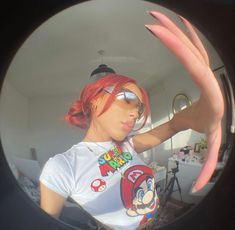 a woman with red hair and sunglasses is taking a selfie in a round mirror