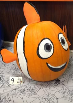 an orange and white clown fish pumpkin sitting on top of a table next to numbers