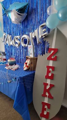 a table with balloons and decorations for a shark themed birthday party at a children's playroom