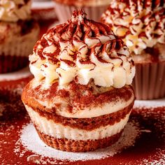 several cupcakes with white frosting and chocolate sprinkles on top