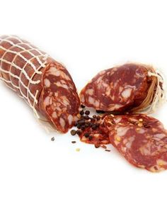 three slices of salami in a mesh bag on a white background with spices scattered around it