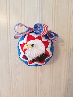 an american eagle ornament hanging on a white door with red, white and blue ribbon