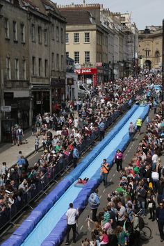 a crowd of people walking down a street next to tall buildings with blue tarps