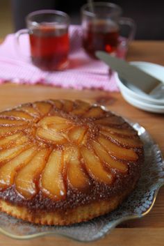 a pineapple upside down cake sitting on top of a glass plate next to a cup